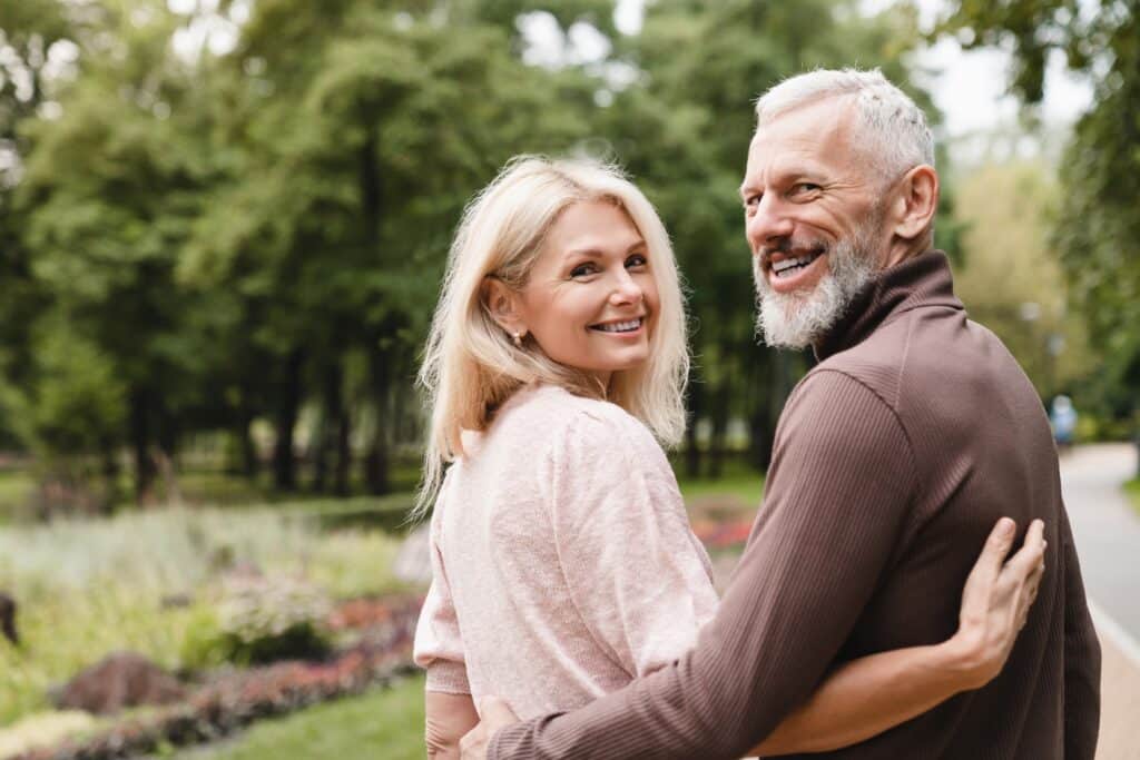 Smiling,Happy,Caucasian,Mature,Spouses,Hugging,Embracing,While,Walking,On A man and woman smiling after receiving femoral hernia care in New Orleans 1
