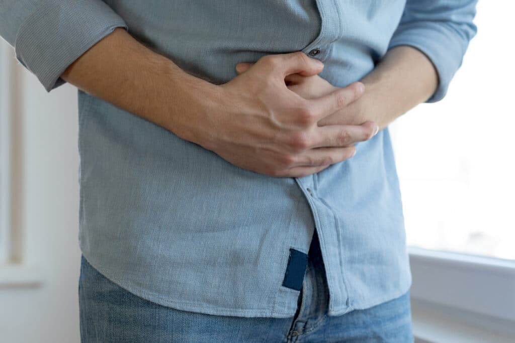 Man holding his upper abdomen due to hiatal hernia-related stomach discomfort.